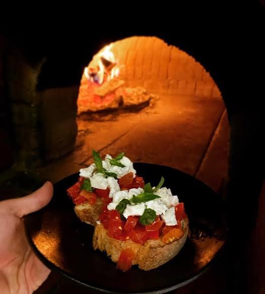 Bruschetta held in front of the flames in the wood-fired oven