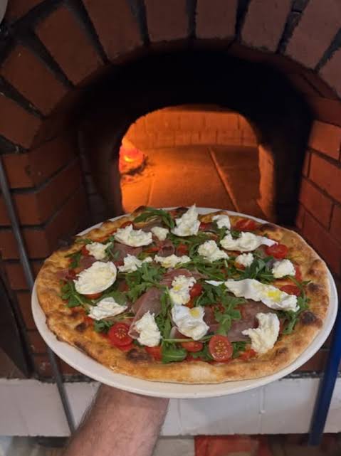Pizza coming out of the wood-fired oven